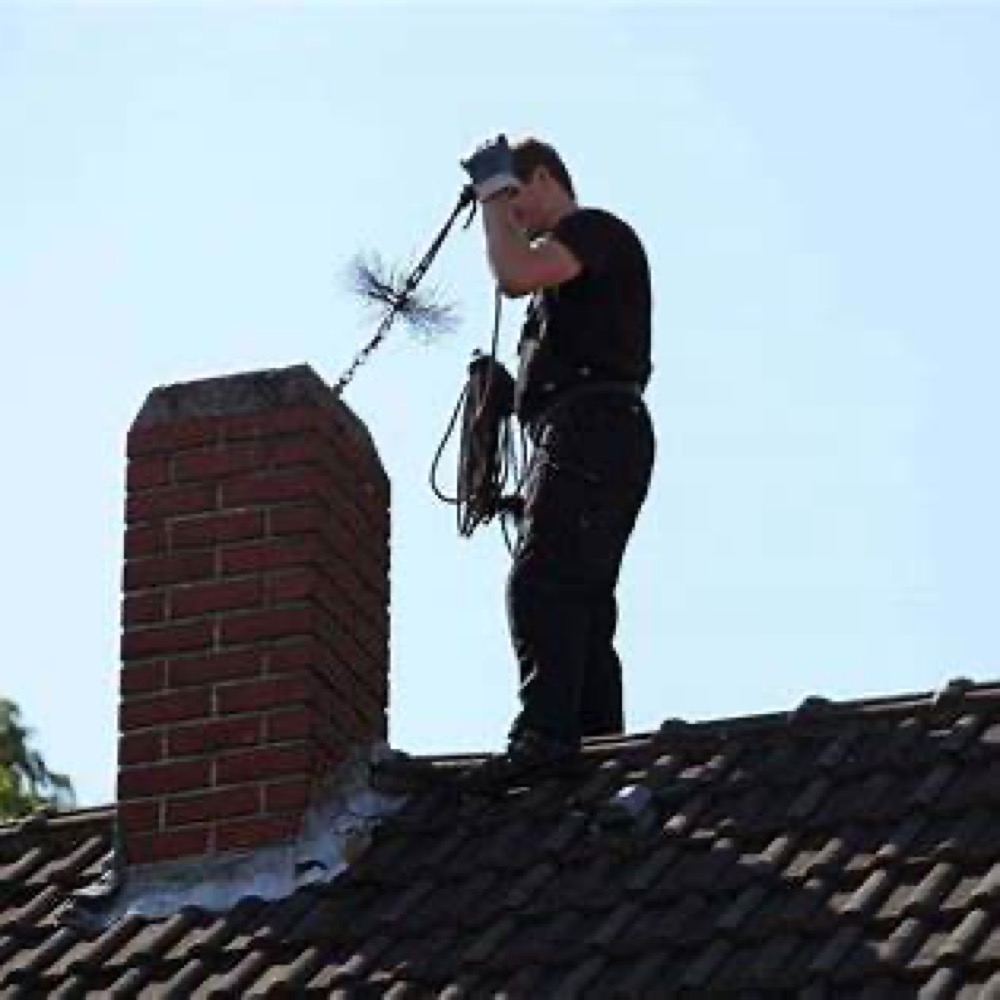 Chimney technician sweeping a chimney from the roof